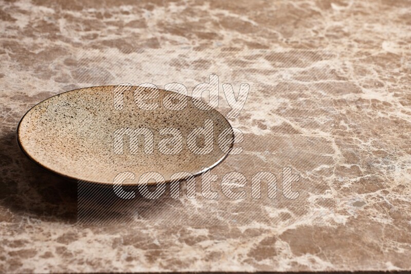 A multicolored pottery plate on beige marble background