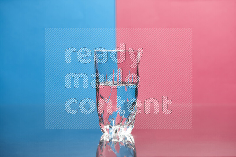 The image features a clear glassware filled with water, set against blue and pink background