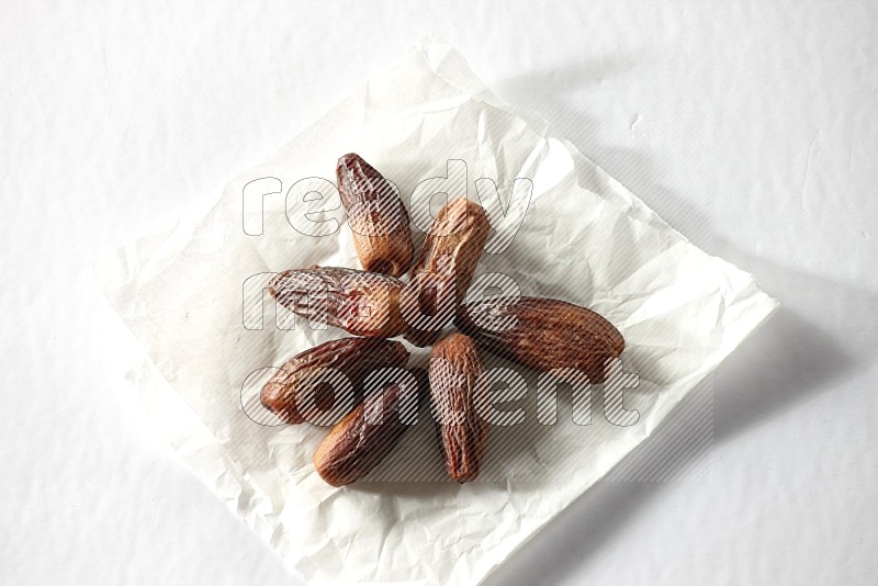 Dried dates on a crumpled piece of paper on a white background in different angles