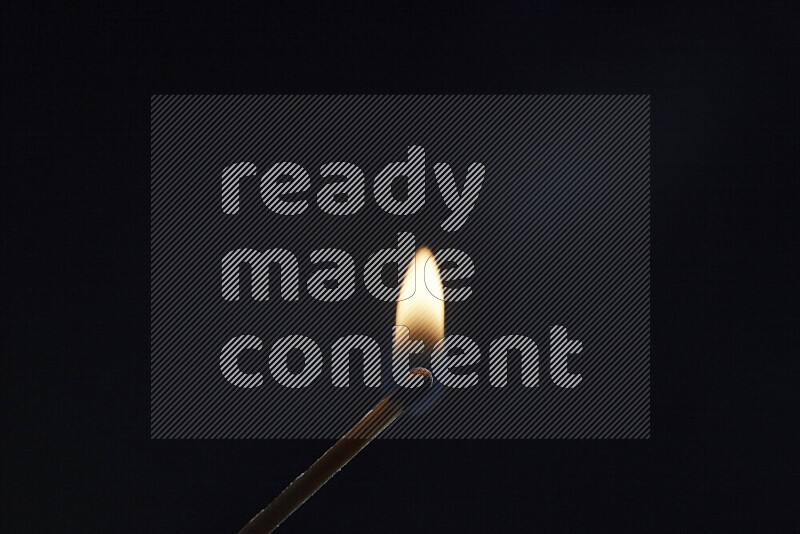 A burning matchstick isolated on dark backdrop