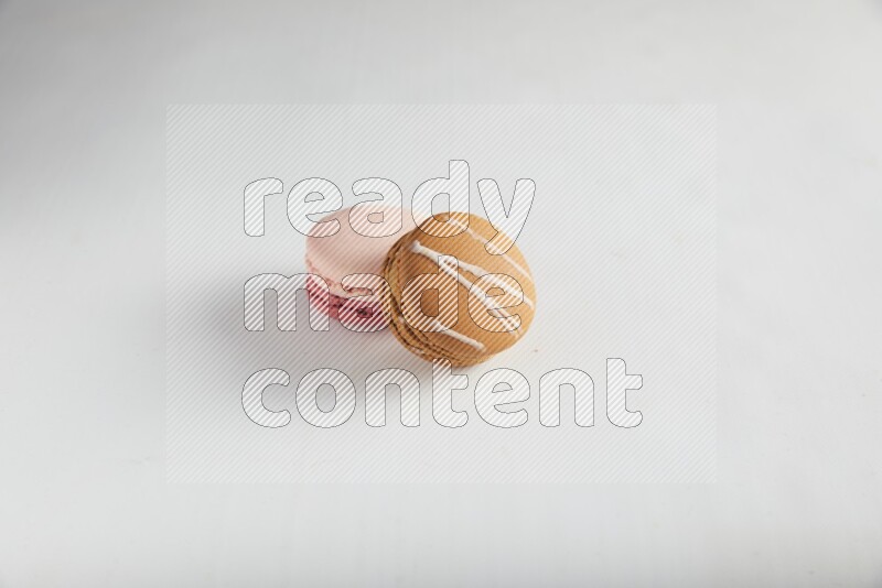45º Shot of of two assorted Brown Irish Cream, and Pink Litchi Raspberry macarons on white background