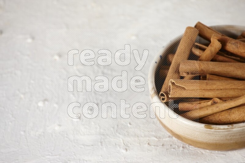 Cinnamon sticks in a ceramic bowl in different angles on white background