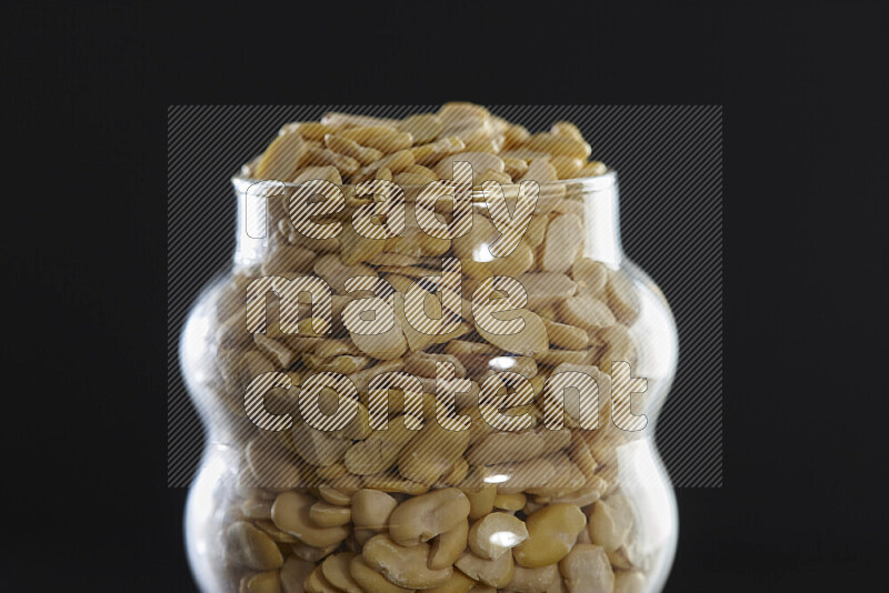 Crushed beans in a glass jar on black background