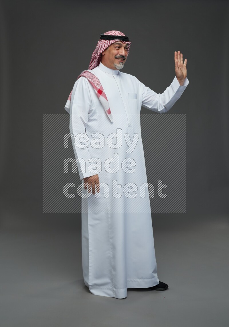 Saudi man with shomag Standing Interacting with the camera on gray background