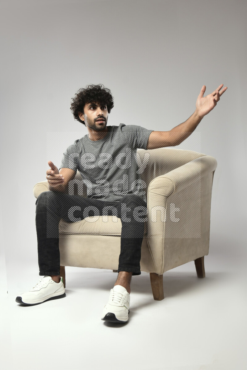 A man wearing casual sitting on a chair making a hand gesture on white background