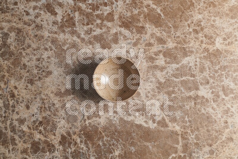 A beige pottery bowl on beige marble background