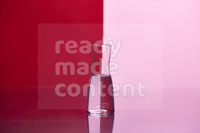 The image features a clear glassware filled with water, set against red and rose background