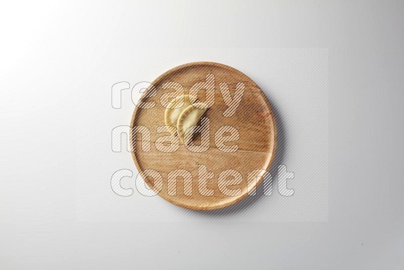 Two Sambosas on a wooden round plate on a white background
