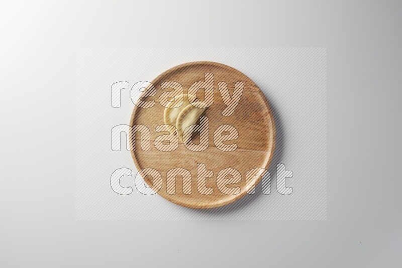 Two Sambosas on a wooden round plate on a white background