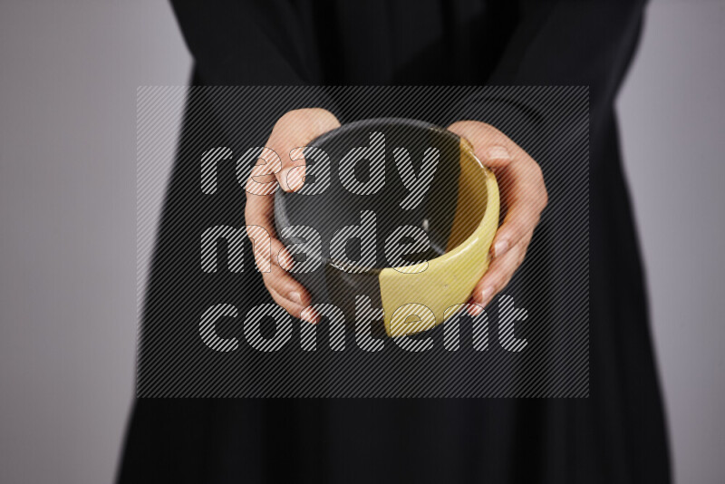 A woman in black abaya holding different pottery essentials in different positions
