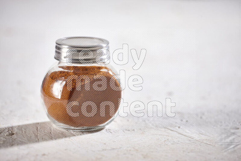 A glass jar full of ground paprika powder on white background