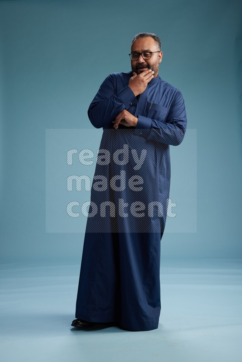Saudi Man without shimag Standing Interacting with the camera on blue background