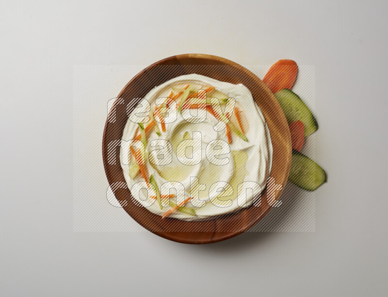 Lebnah garnished with sliced carrots & cucumber in a wooden plate on a white background