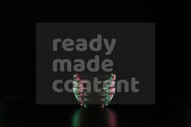 Glassware with rim light in red and green against black background