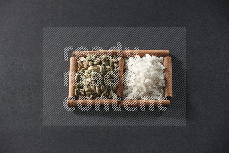 2 squares of cinnamon sticks full of white salt and cardamom on black flooring