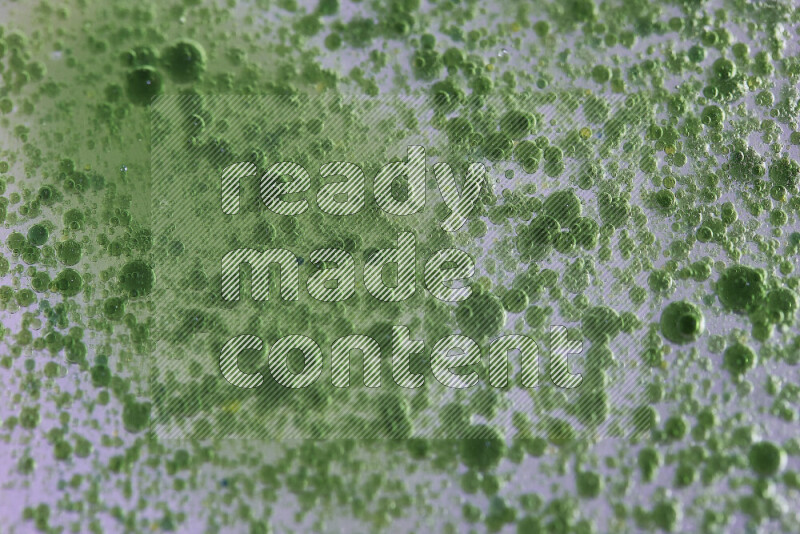 لقطات مقربة لقطرات ألوان مائية خضراء على سطح الزيت على خلفية بيضاء