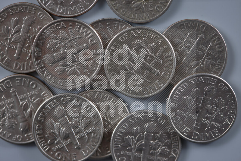A close-up of scattered United States one dime coins on grey background