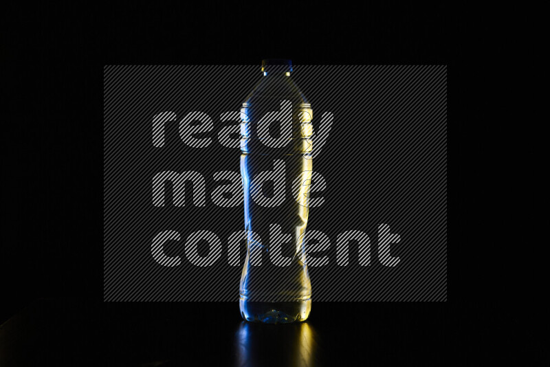 Water bottle with colored rim light against black background