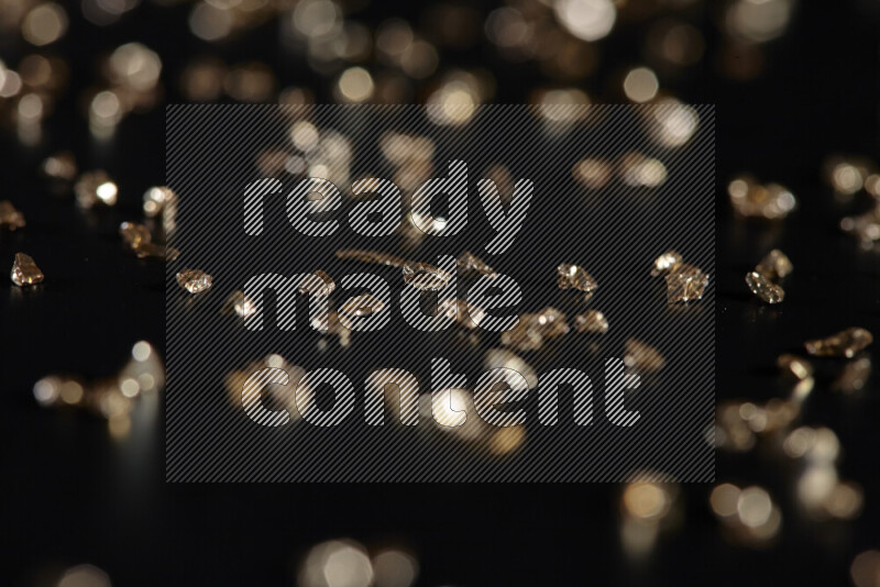 Gold shimmering fragments of glass scattered on a black background