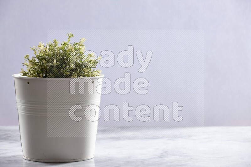 Artificial plant in white pot on grey marble background