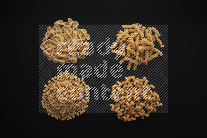 Different pasta types in bunches on black background