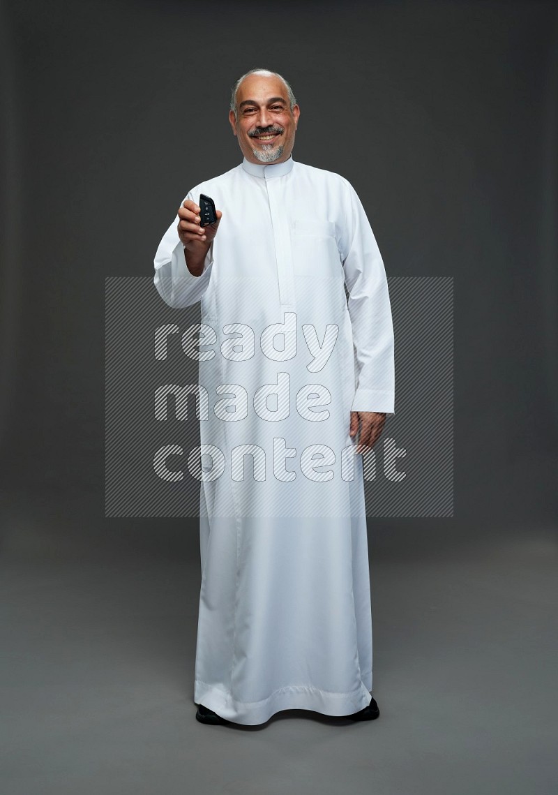 Saudi man without shomag Standing holding car key on gray background