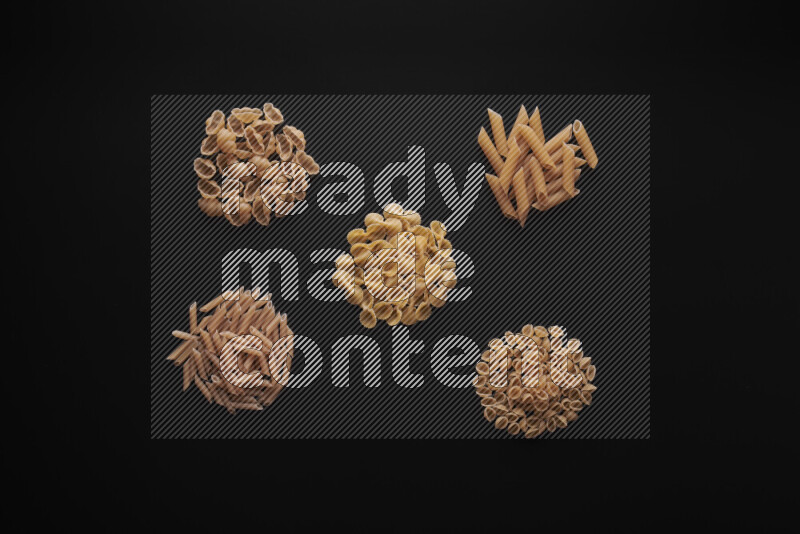 Different pasta types in bunches on black background
