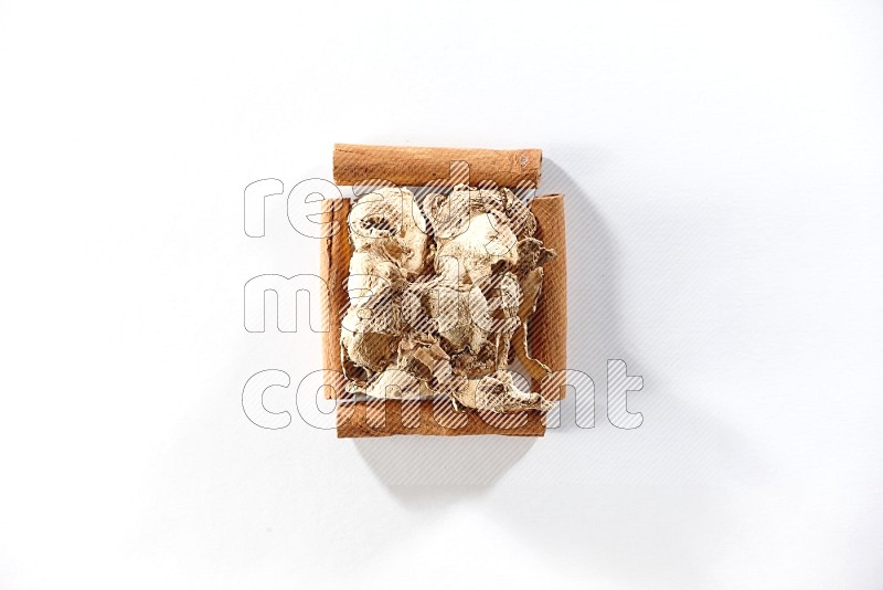 A single square of cinnamon sticks full of dried ginger on white flooring