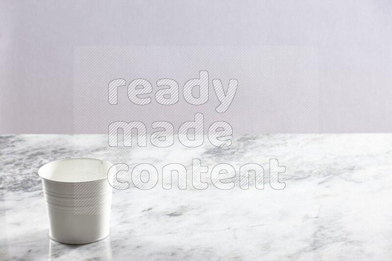 An empty white plant pot on grey marble background