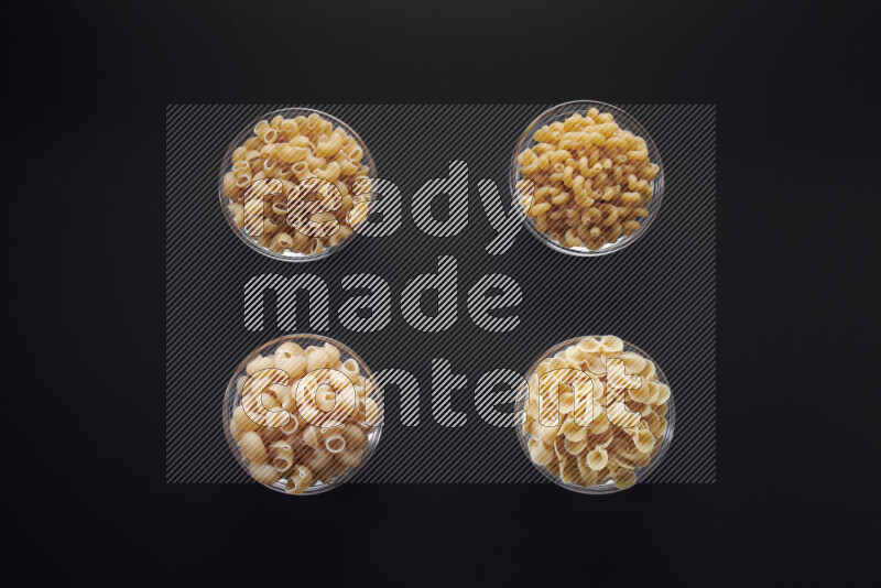 أنواع مختلفة من المعكرونة في وعاء زجاجي علي خلفية سوداء