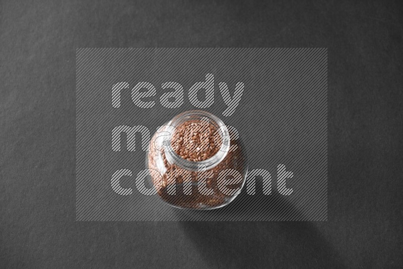 A glass spice jar full of flax on black flooring