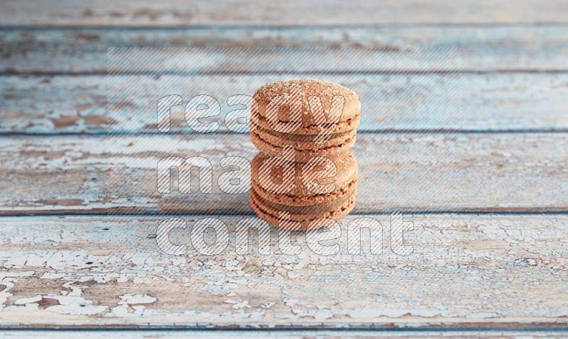 45º Shot of two Brown Hazelnuts macarons on light blue wooden background