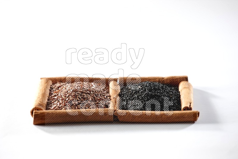 2 squares of cinnamon sticks full of flaxseeds and black seeds on white flooring
