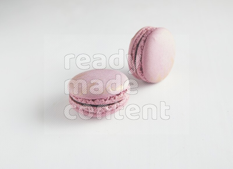 45º Shot of two Purple Strawberry macarons on white background