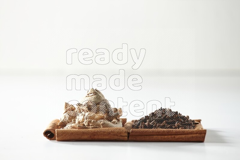 2 squares of cinnamon sticks full of cloves and dried ginger on white flooring