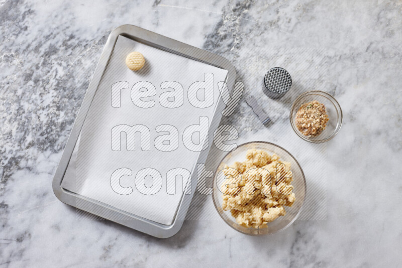 كحك خطوة بخطوة بمكوناته سمن، سكر، دقيق، سمسم، خميرة، ماء ونكهة الكحك على خلفية رخام رمادي