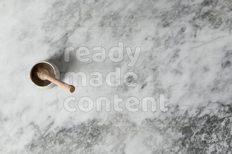 Beige pottery bowl with wooden honey dipper in it on grey marble background