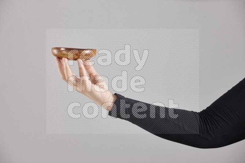 A woman in black abaya holding different wooden essentials in different positions