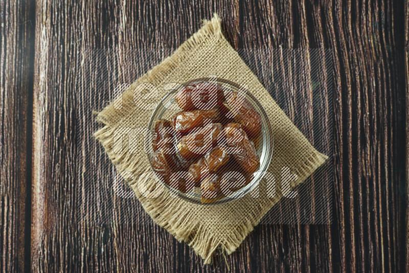 Dates in different bowls (wooden, pottery and glass) on wooden background