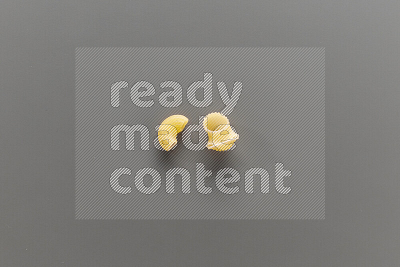 Elbow pasta with other types of pasta on grey background