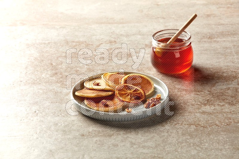Five stacked dried orange mini pancakes in a blue plate on beige background