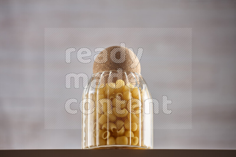 Raw pasta in glass jars on beige background