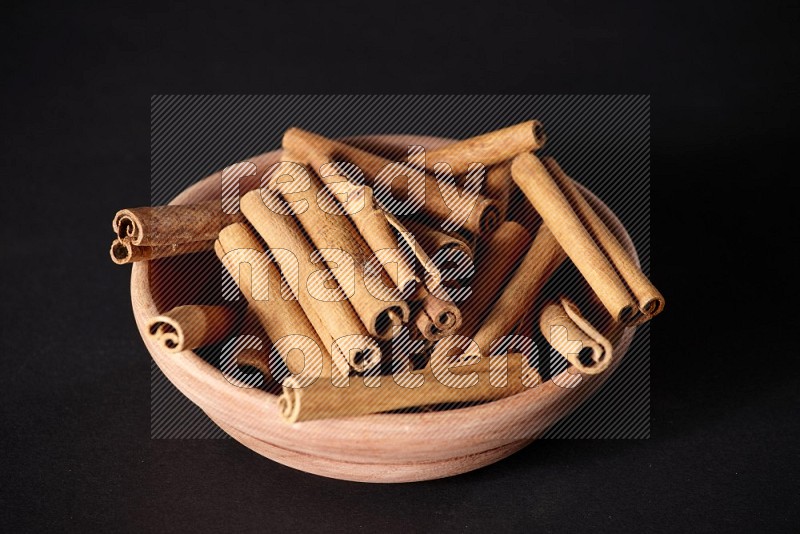 Cinnamon Sticks in a wooden bowl on black background