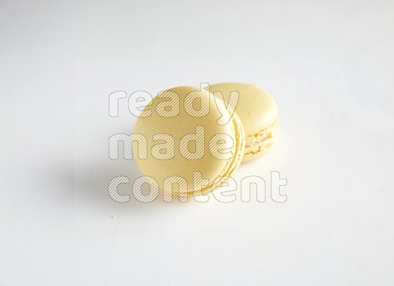 45º Shot of two Yellow Vanilla macarons on white background