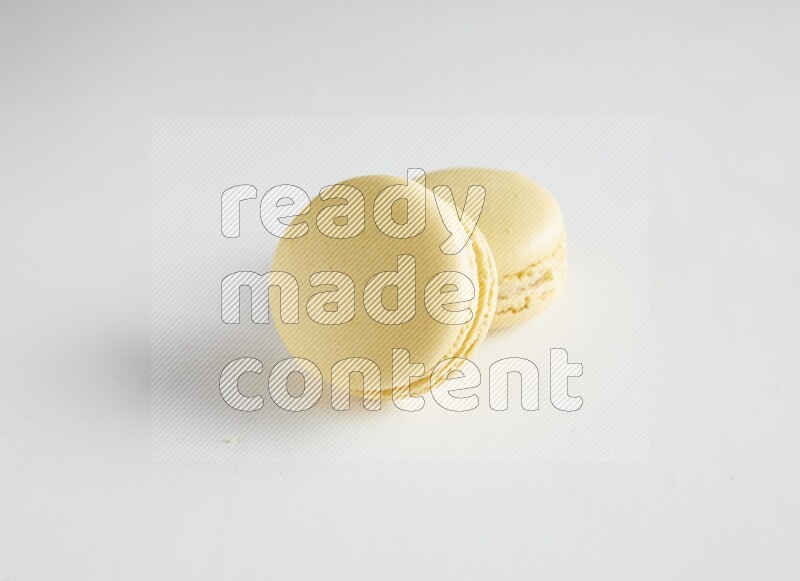 45º Shot of two Yellow Vanilla macarons on white background