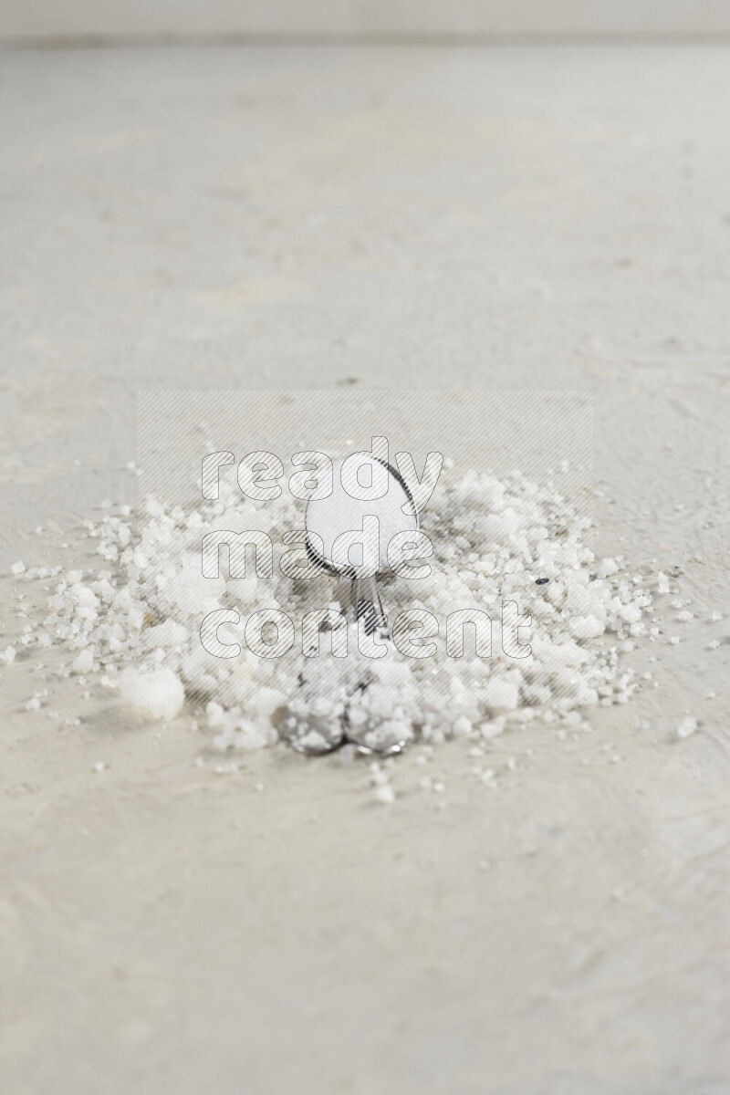 2 metal spoons filled with fine table salt and fine pink himalayan salt on white background