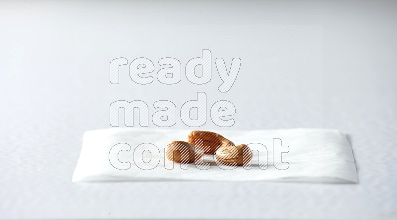 3 cashews on a piece of paper on a white background in different angles