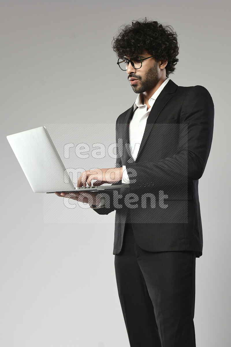 A man wearing formal standing and working on a laptop on white background