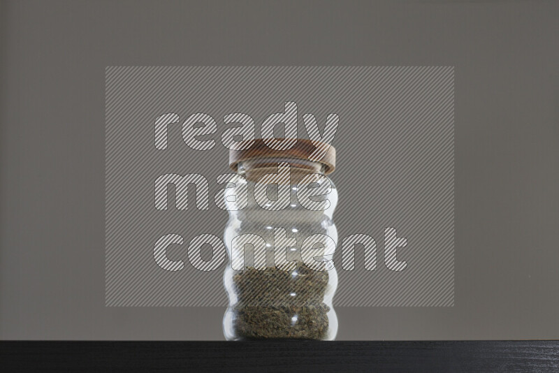 Dried basil in a glass jar on black background