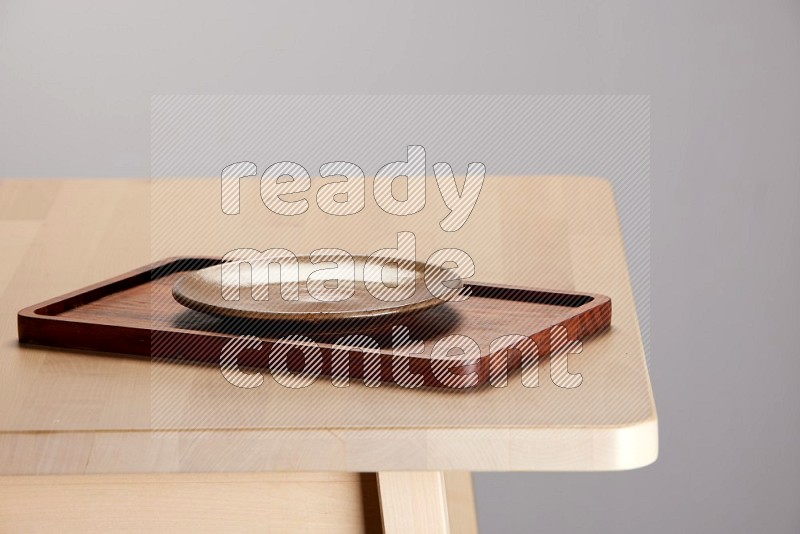 multi-colored pottery Plate placed on a rectangular wooden tray on the edge of wooden table